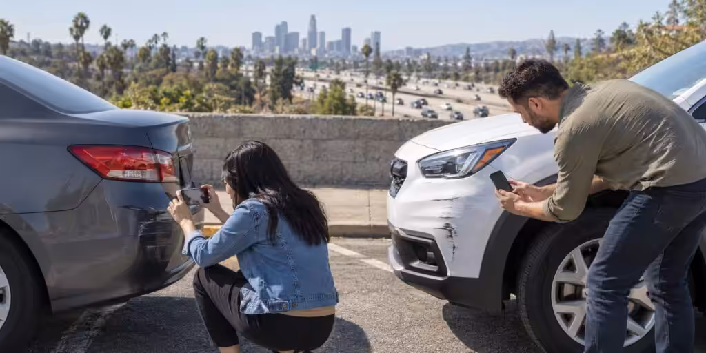 Illustrative scene of two drivers photographing vehicle damage after a freeway rear-end collision near Los Angeles